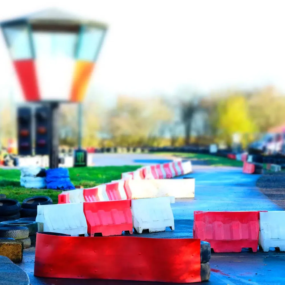 Go-kart track with red and white barriers lining the blue tarmac course and a colourful start gantry in the background.