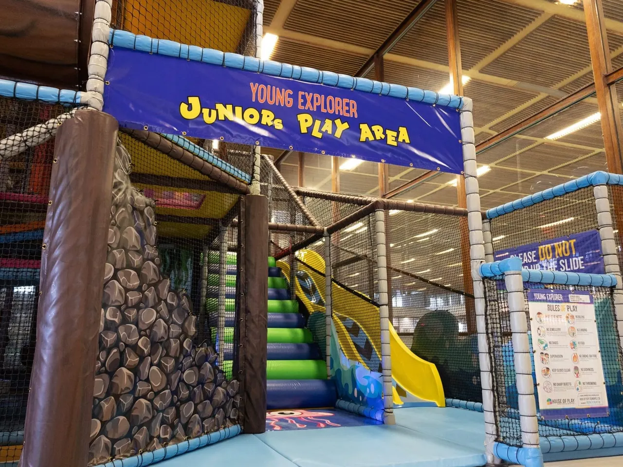 Indoor soft play area with climbing wall, slide and net structures for young children.