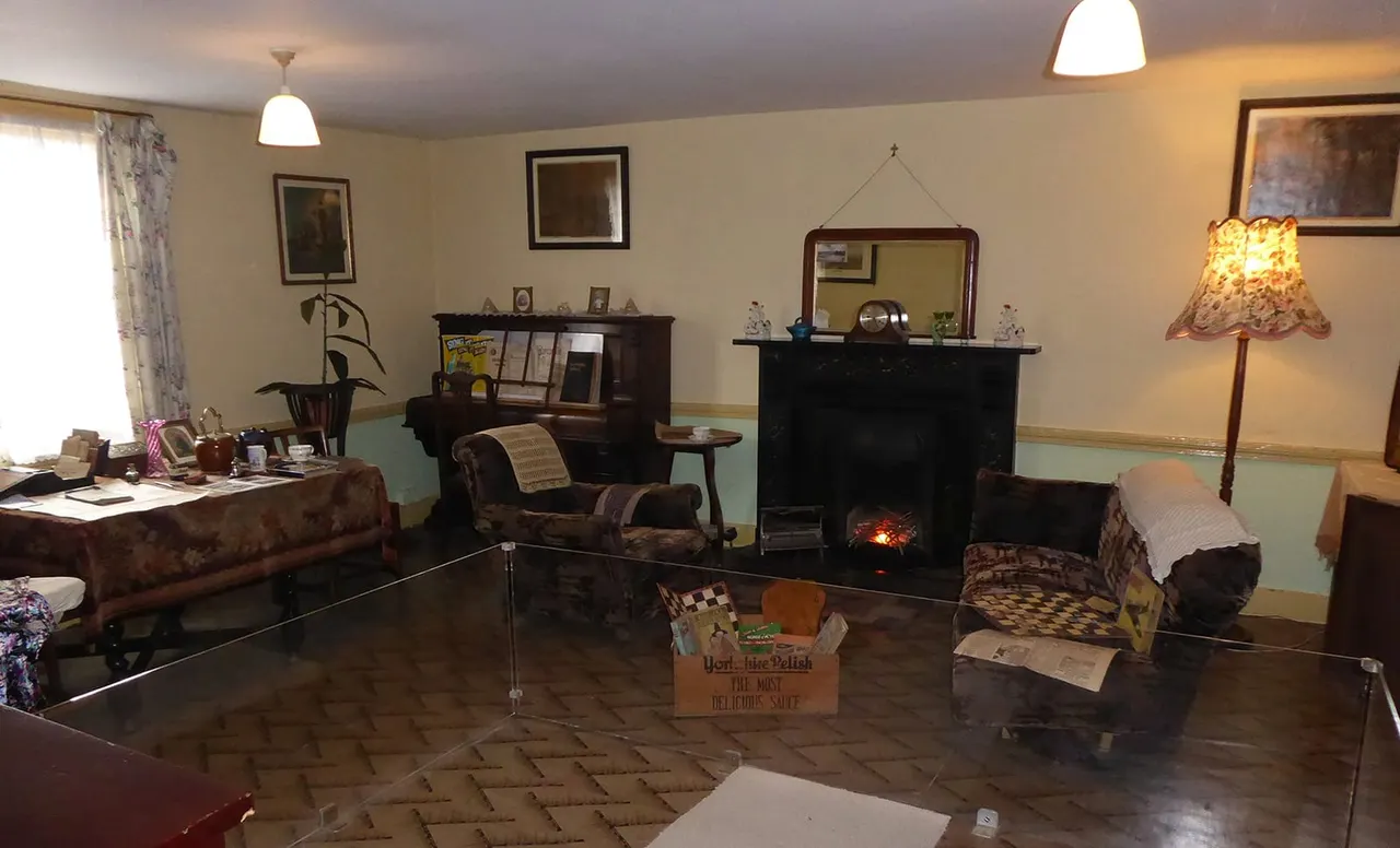 A period room display showing a vintage living room with furniture, fireplace, and domestic items from an earlier era.