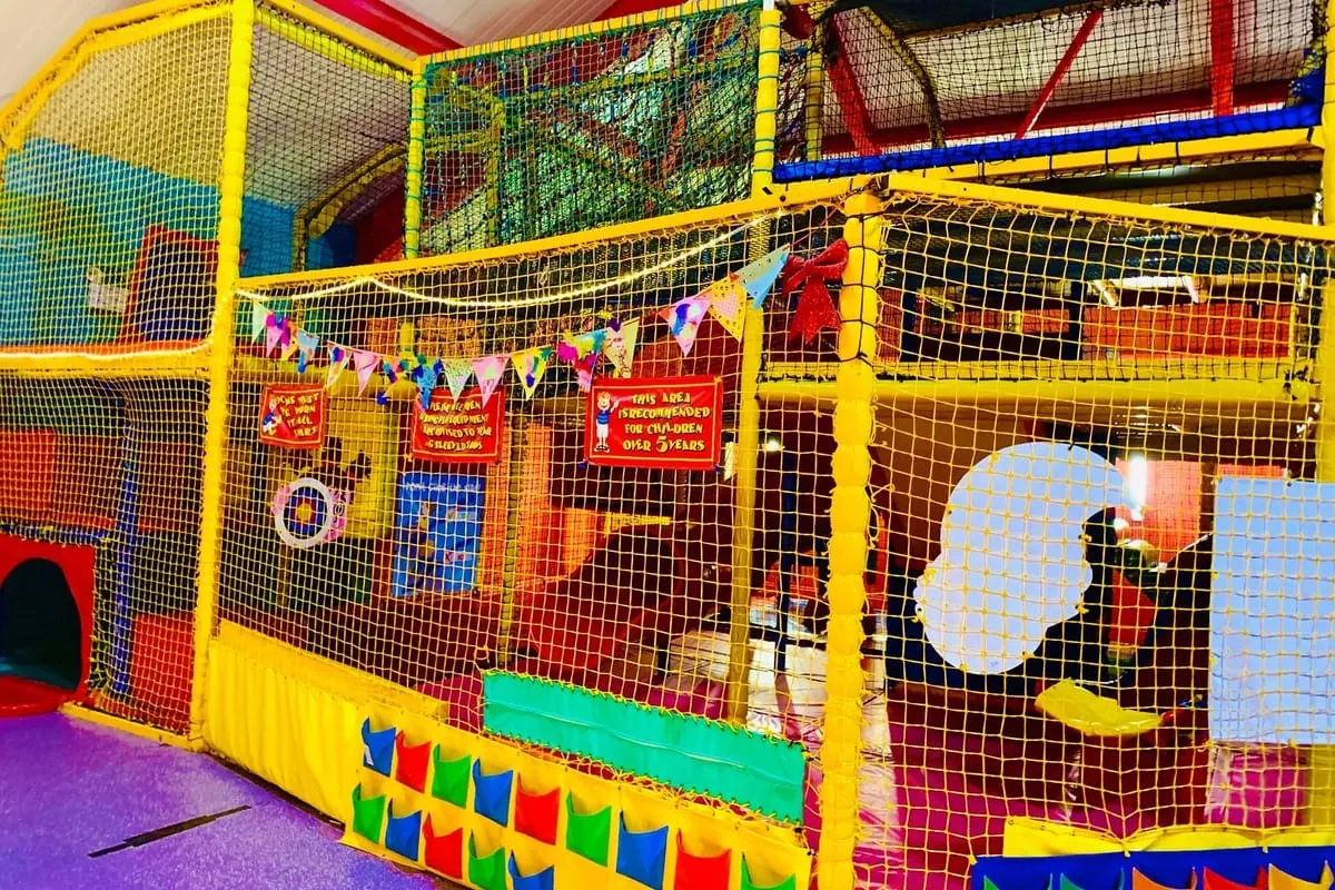 Colourful indoor play structure with netting and yellow frames, designed for young children to climb and explore.