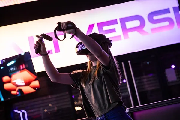 Person wearing a VR headset and holding controllers in an immersive gaming experience.