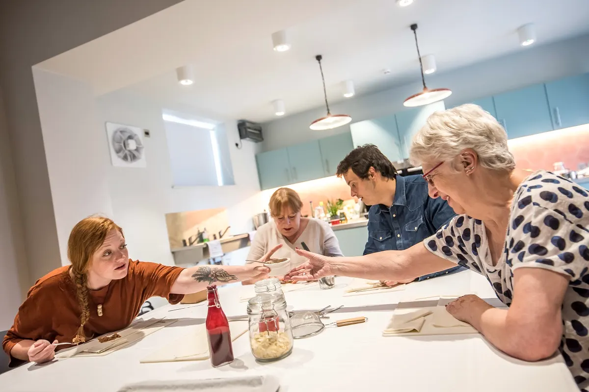 Family participating in a hands-on cooking or food preparation activity at a modern kitchen counter.