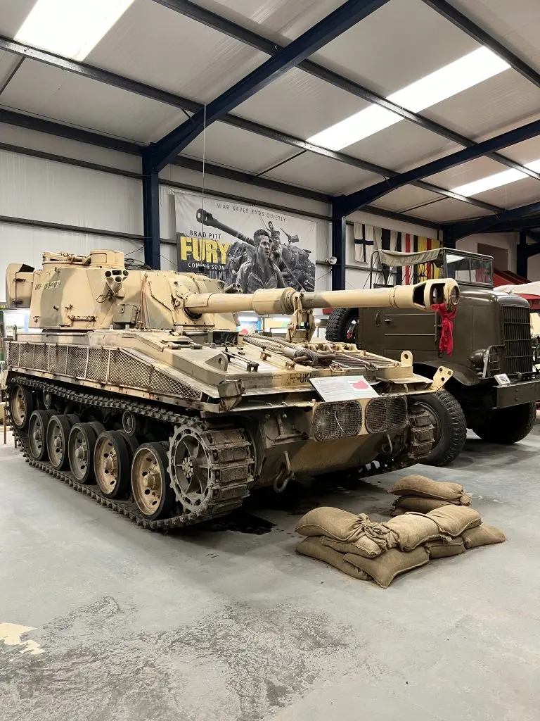Historic military vehicles including a tank and truck displayed in an indoor museum hangar.