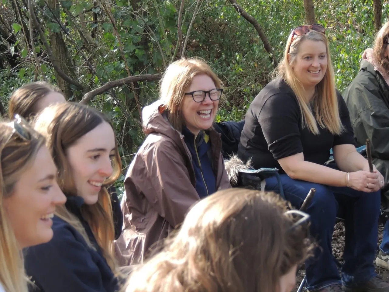 Group of smiling young people gathered among trees during an outdoor forest activity.