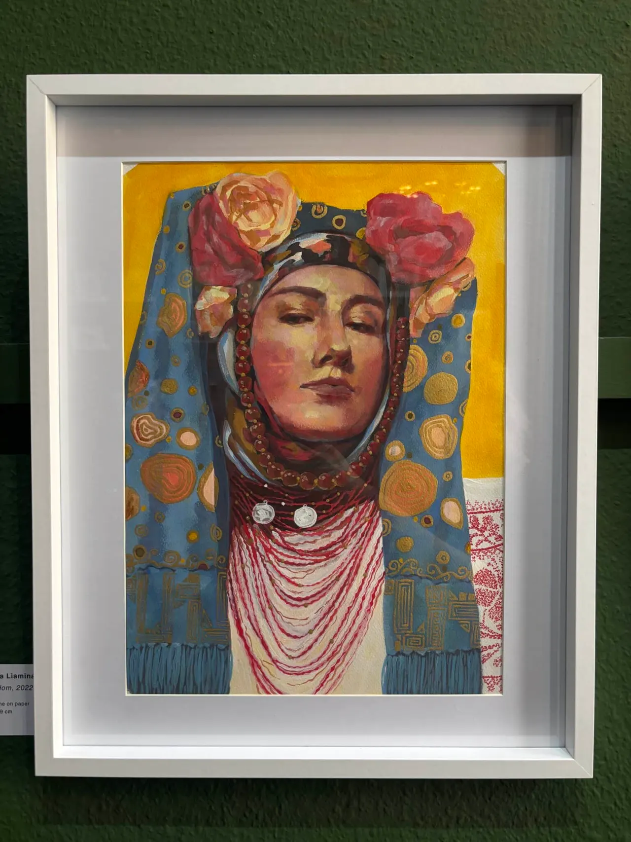 Framed artwork depicting a person in traditional Russian costume with red roses, ornate headwear and beaded necklaces against a golden yellow background.