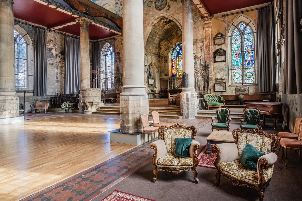 Historic church interior with ornate columns, stained glass windows, and period furniture arranged in the nave.