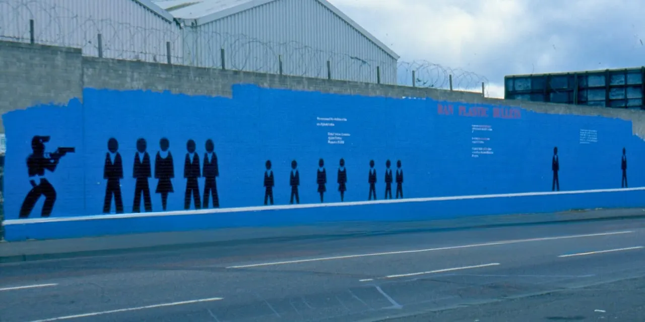 Large blue mural on a security wall depicting silhouetted figures in historical attire, viewed from across a road.