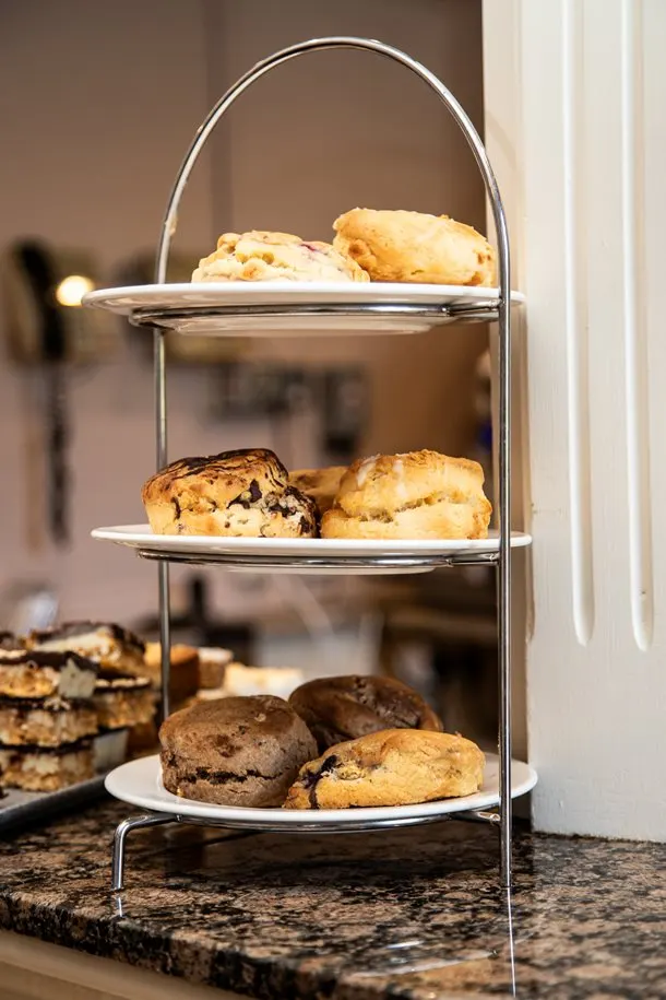 Three-tiered stand displaying assorted freshly baked scones and biscuits in a tea room.