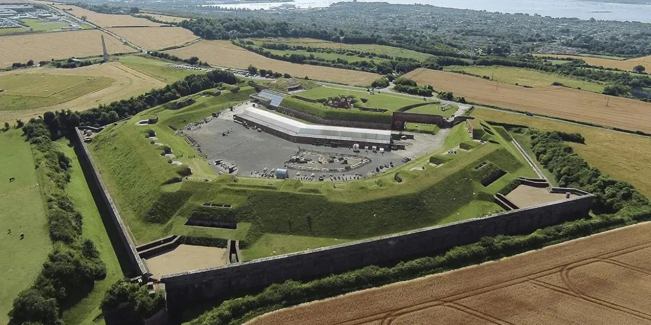 Aerial view of Fort Nelson, a star-shaped fortification with grass ramparts, modern visitor building, and surrounding countryside.