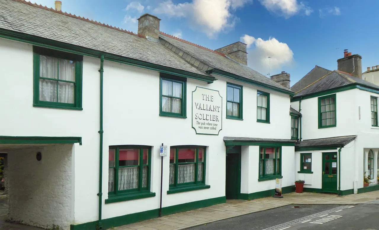 Traditional white-walled pub with green trim and windows, stone chimneys visible on the slate roof.