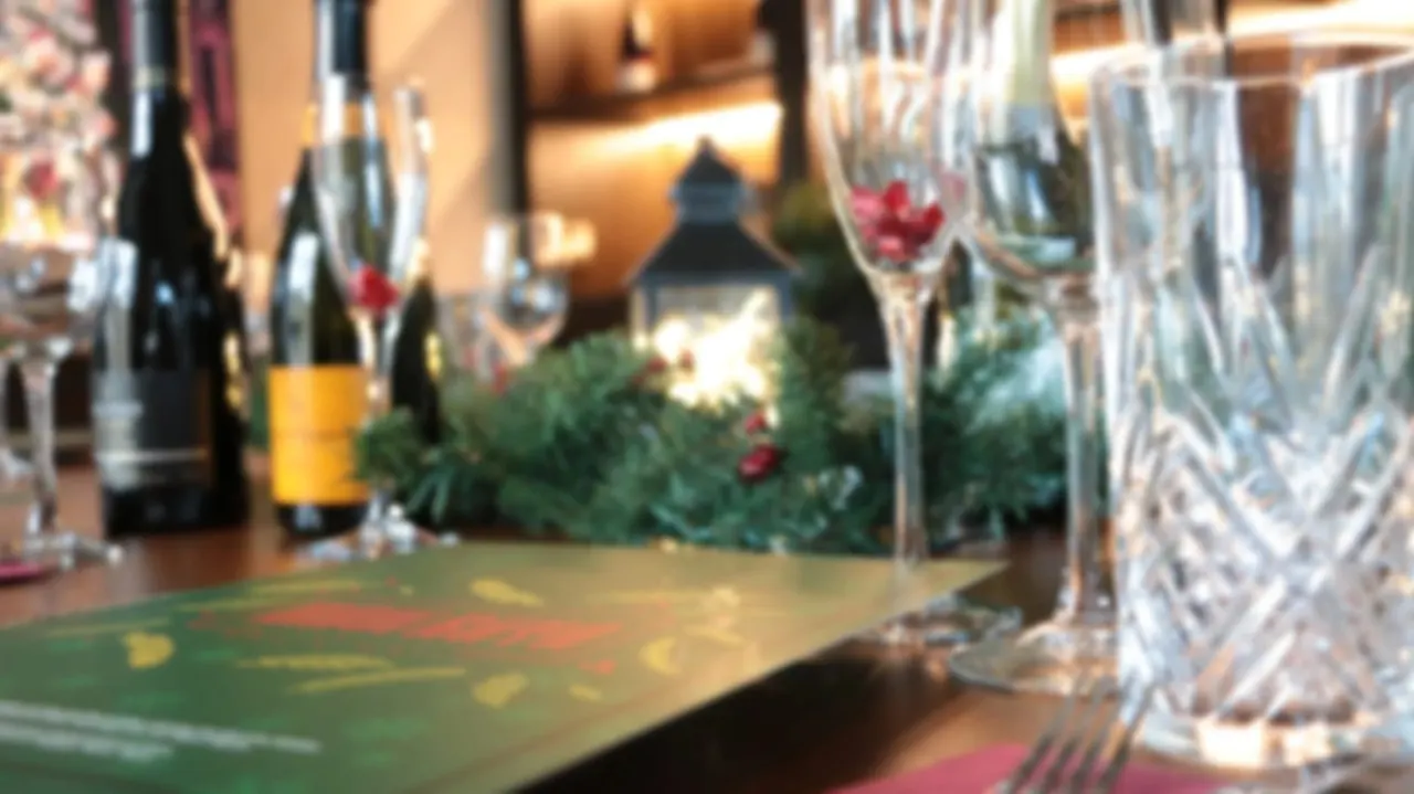 Wine glasses and bottles arranged on a dining table with festive decorations and greenery.