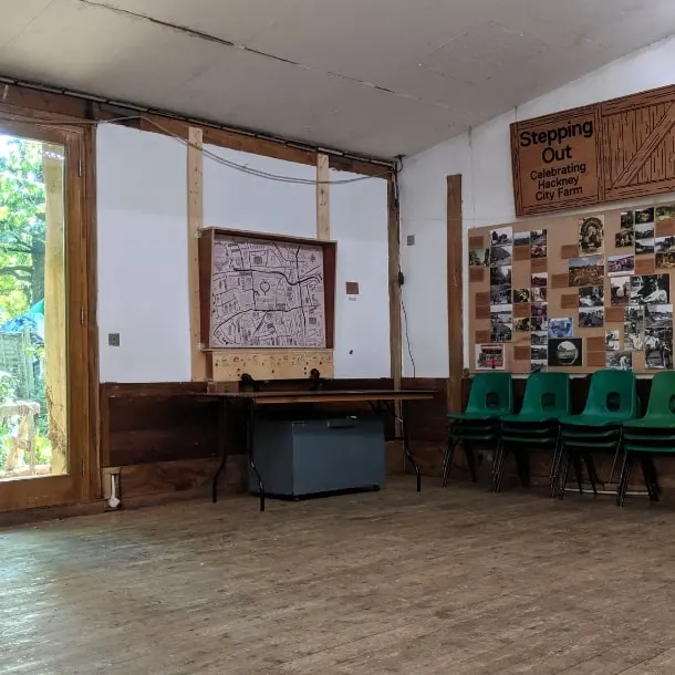 Interior of farm visitor centre with wooden display boards, green chairs, and photographs on walls.