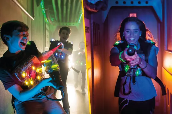 Children playing laser tag indoors with illuminated vests and guns in a neon-lit arena.