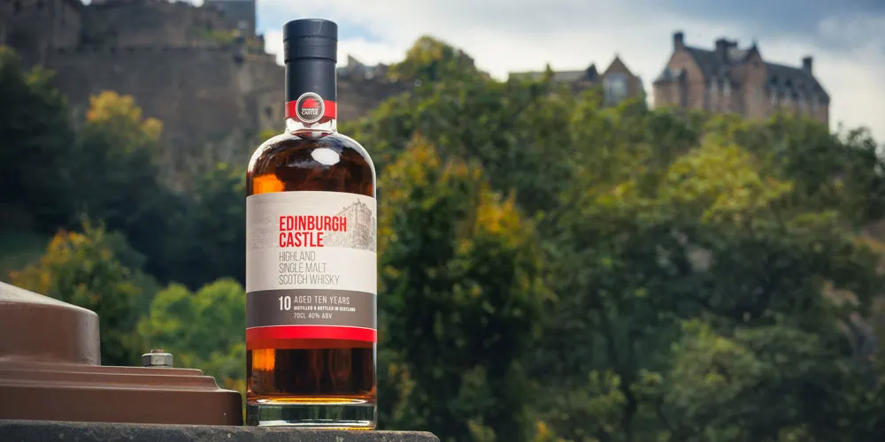 Bottle of Edinburgh Castle Highland single malt Scotch whisky displayed with Edinburgh Castle in the background.