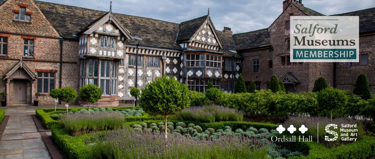 Historic timber-framed and brick manor house with manicured gardens featuring lavender and topiary shrubs.