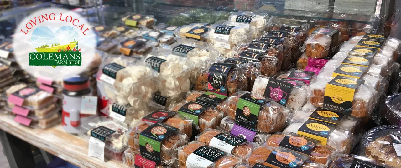 Display cabinet filled with packaged baked goods including cakes, bread and pastries with branded labels.