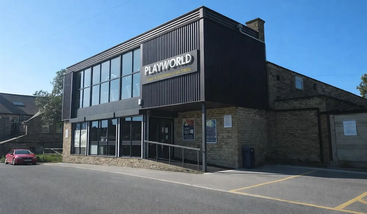 Modern leisure venue building with black cladding and large windows, red car parked outside on clear day.