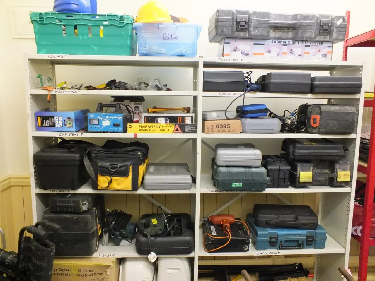 Two white shelving units stocked with tools, equipment boxes, cables and storage containers organised by category.