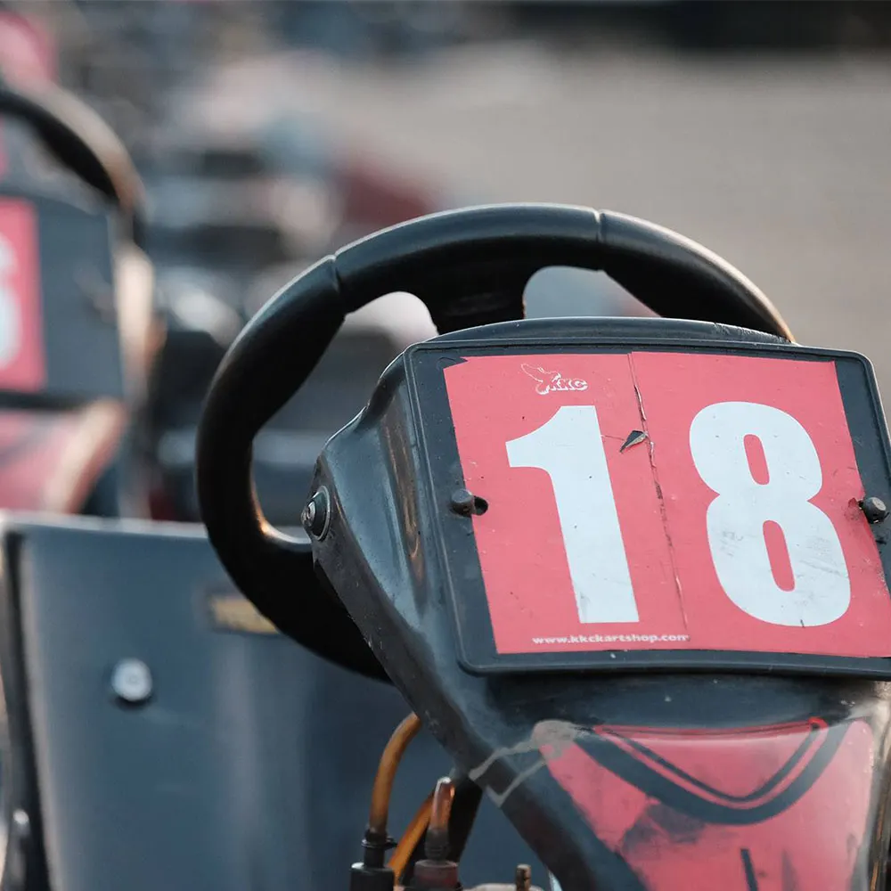 Go-kart with number plate 18 on track at racing venue.
