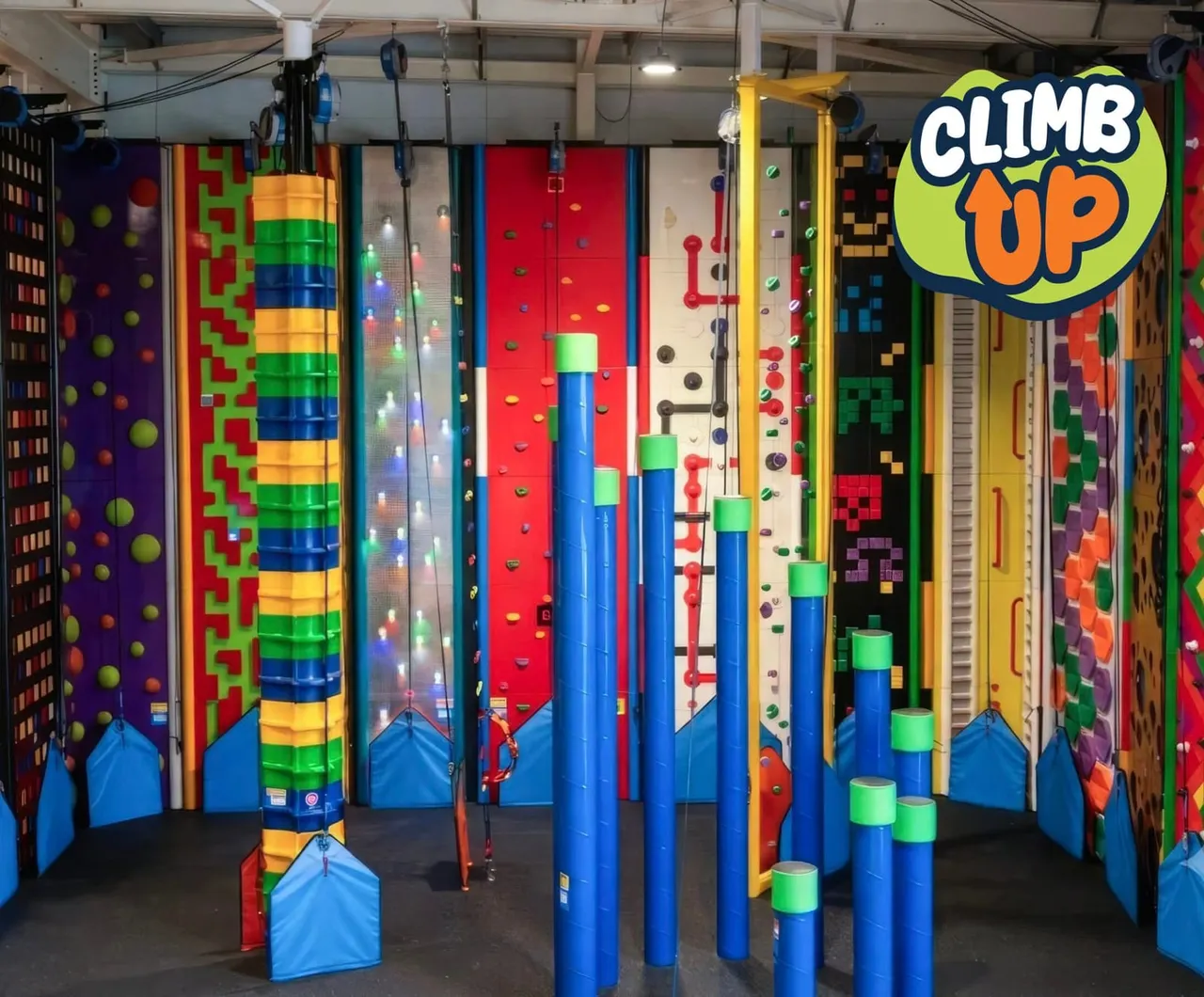 Colourful indoor soft play facility with multiple climbing walls, tubes, and obstacles in bright primary colours.
