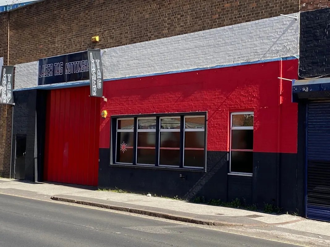Red and black laser tag venue building with signage on a street corner.