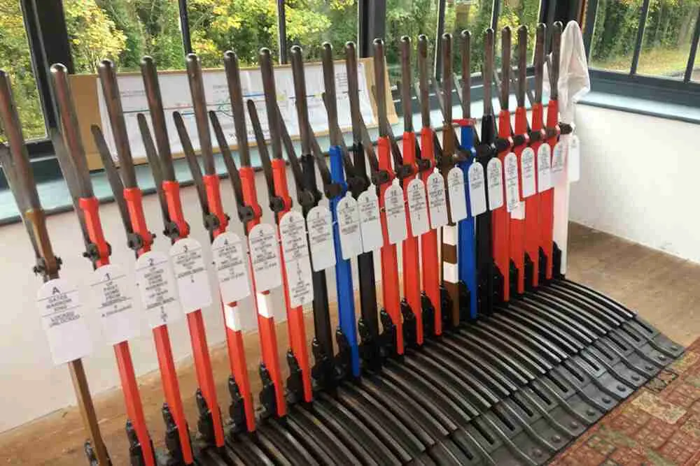 Row of oars with labels lined up indoors near windows, displayed at a railway station venue.