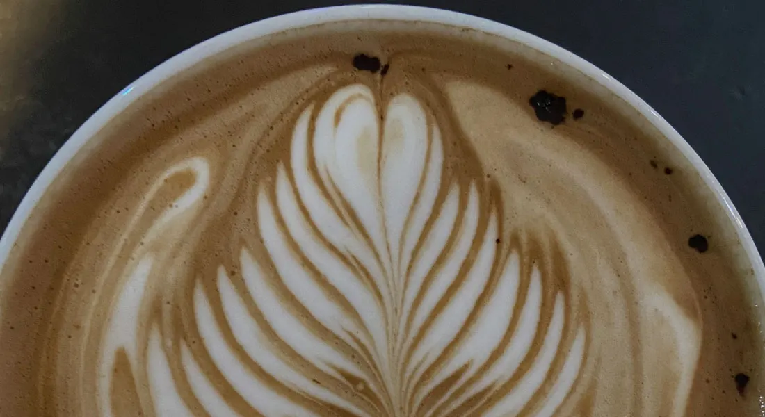 Close-up of a cappuccino with latte art design in a white cup.