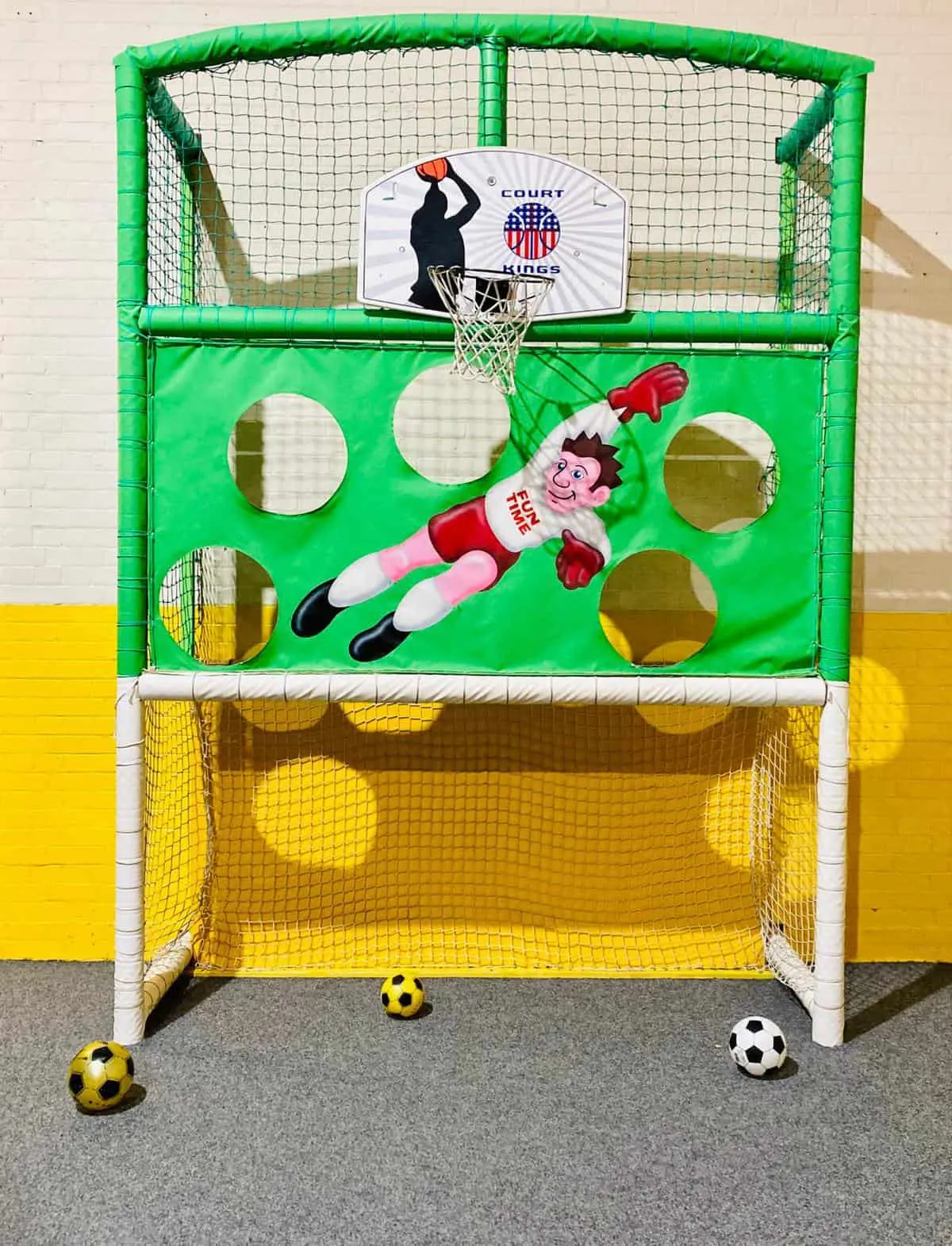 A two-in-one sports game with basketball hoop above and football goal below, decorated with cartoon character graphics.