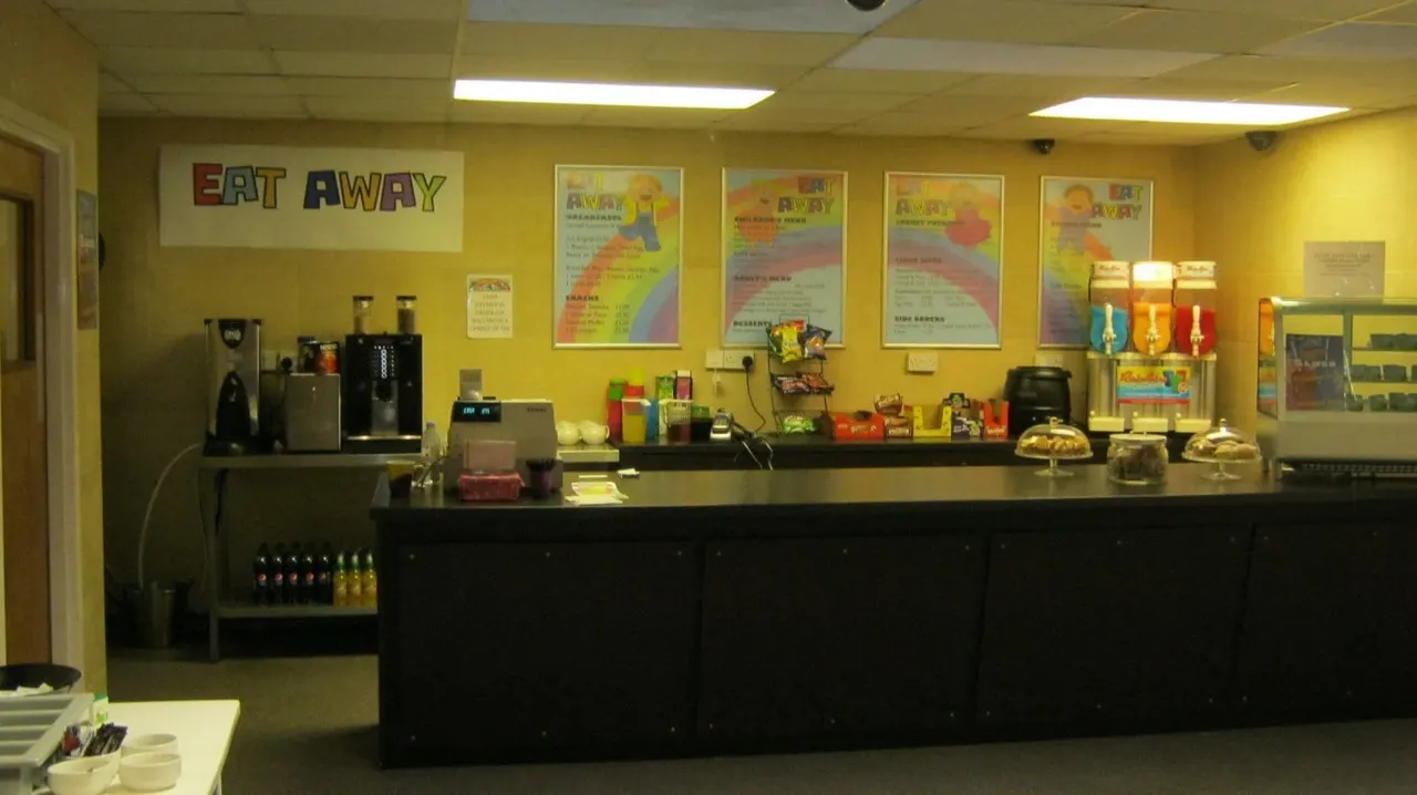 Interior of a takeaway restaurant with yellow walls, service counter, menu boards and food display.