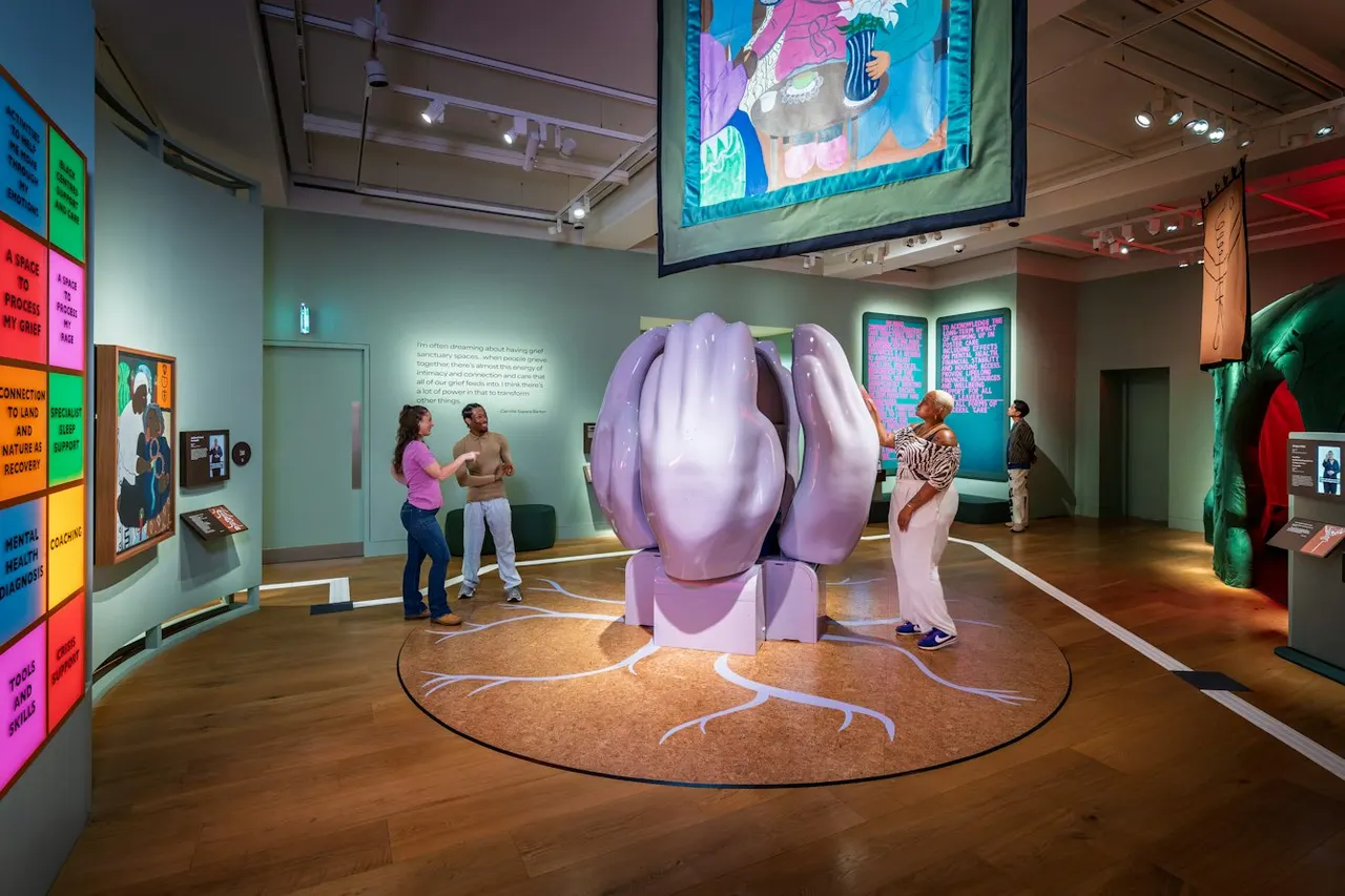 Visitors explore a museum gallery with a large purple sculptural installation and colourful educational displays on the walls.