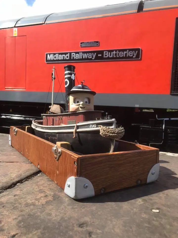 Zug TUGS character model in a display tray in front of Midland Railway-Butterley red stock