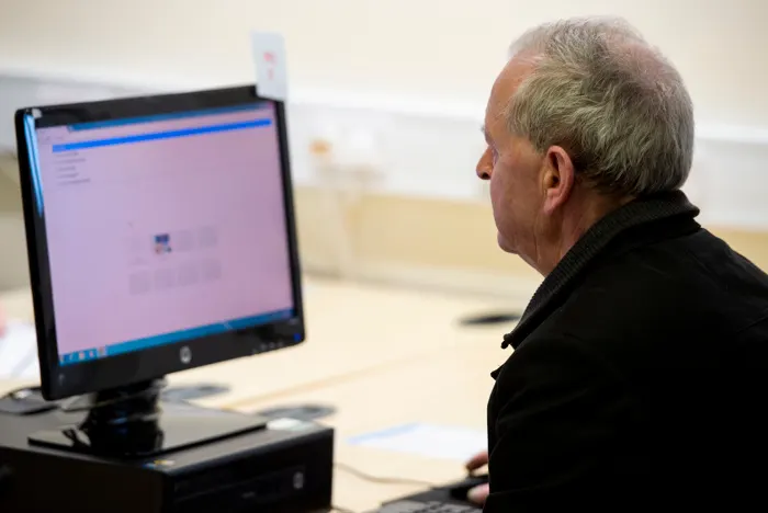 Older man seated at a computer terminal using a library's digital resources.