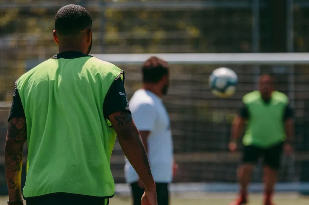 Players in high-visibility training bibs on a football pitch during a match or training session.