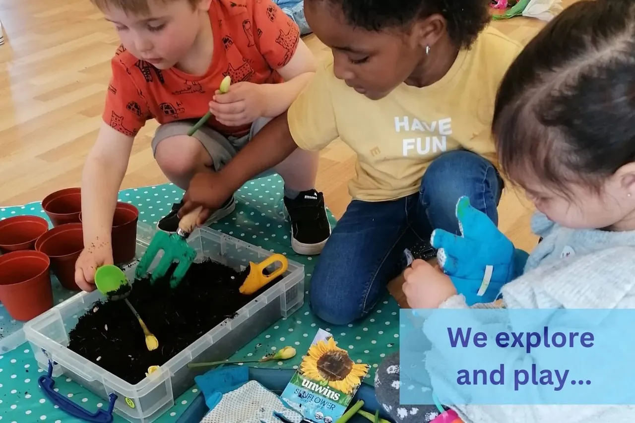 Young children explore a sensory activity with soil and planting tools at an indoor play venue.