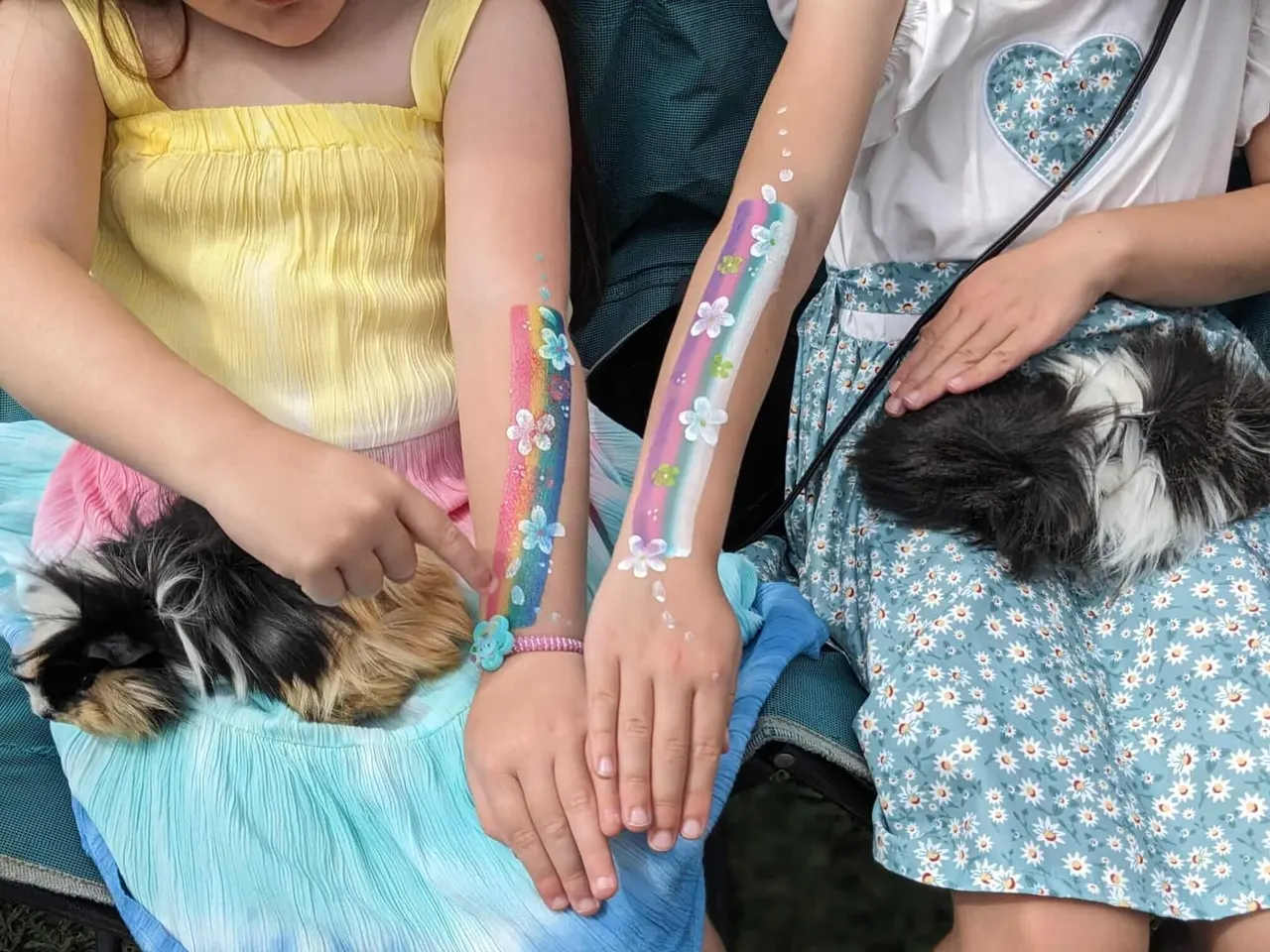 Children displaying temporary arm tattoos and face paint whilst holding small farm animals.