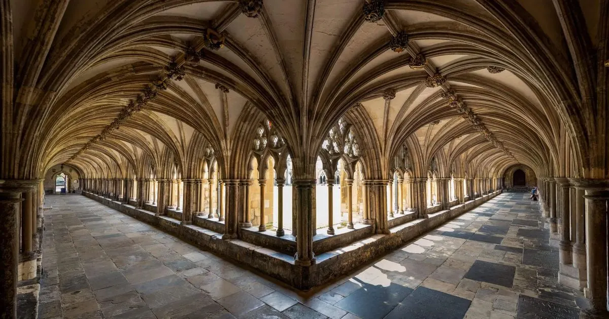 Gothic cathedral cloister with vaulted stone arches, columns and arcading surrounding a central courtyard.