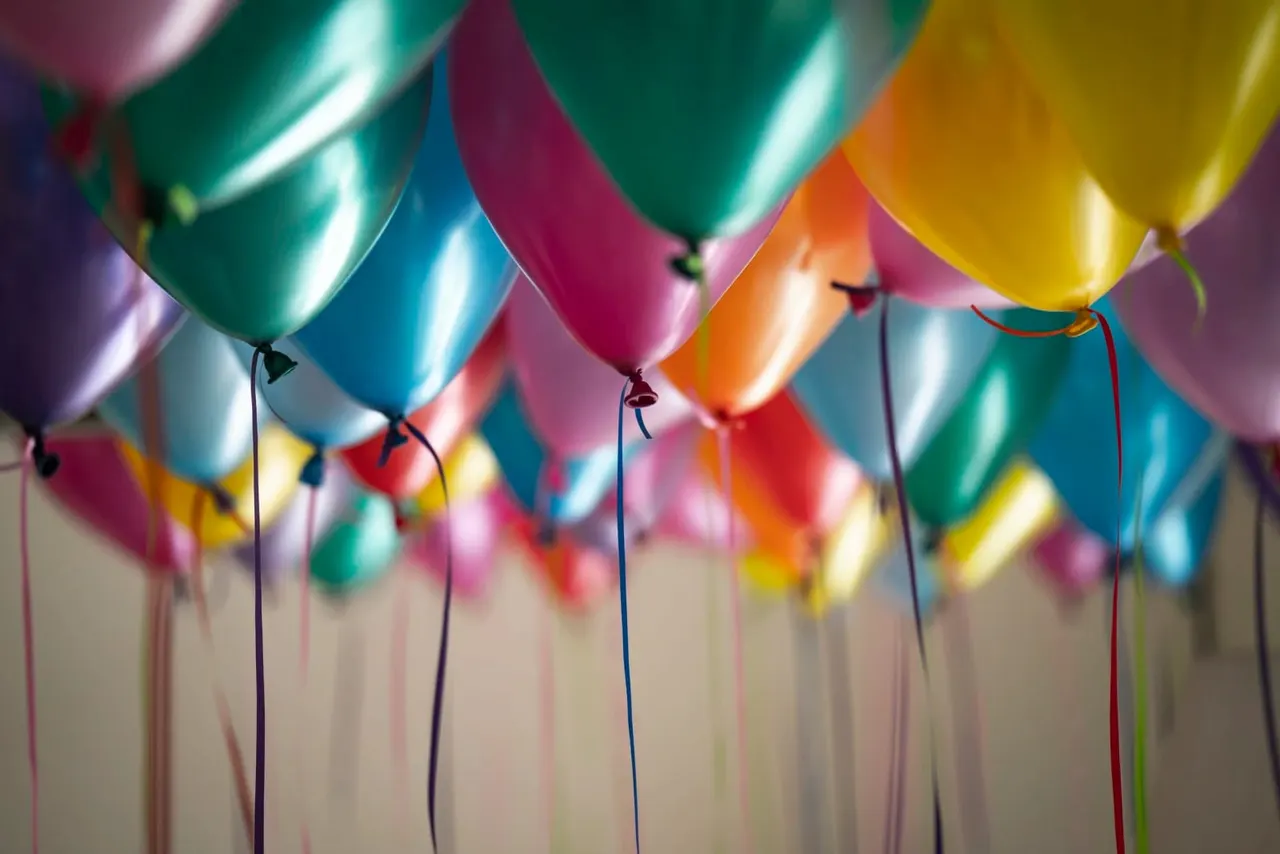 Colourful balloons with strings hanging against a neutral background, ready for a celebration or party decoration.