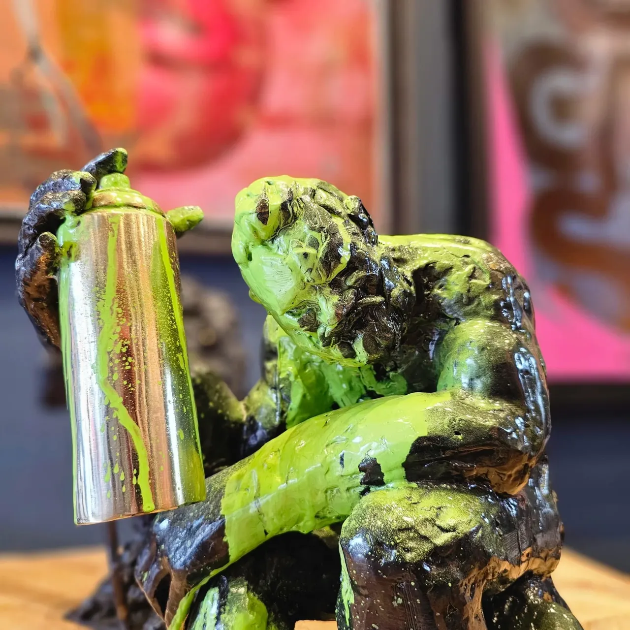 A close-up of a bright lime-green sculptural figure holding a tall cylindrical object, displayed indoors.