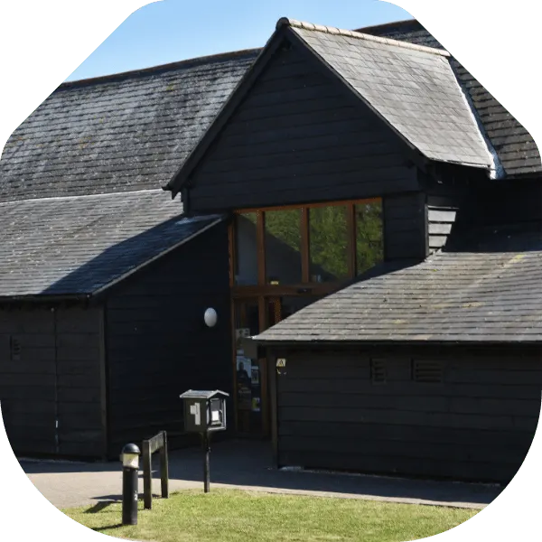 Modern black timber building with slate roof and wooden entrance doors at Hanger Farm Arts Centre.