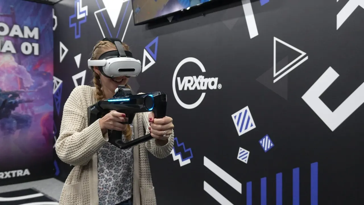 Person wearing a VR headset holding controllers whilst playing a virtual reality game at an entertainment venue.