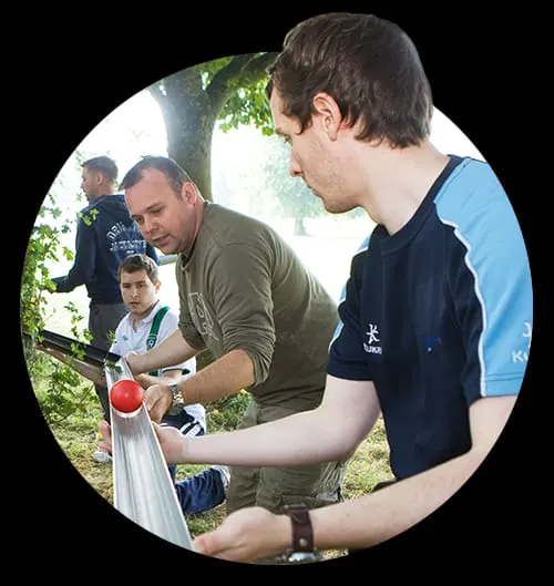 An adult and young people working together at an outdoor activity station in woodland.