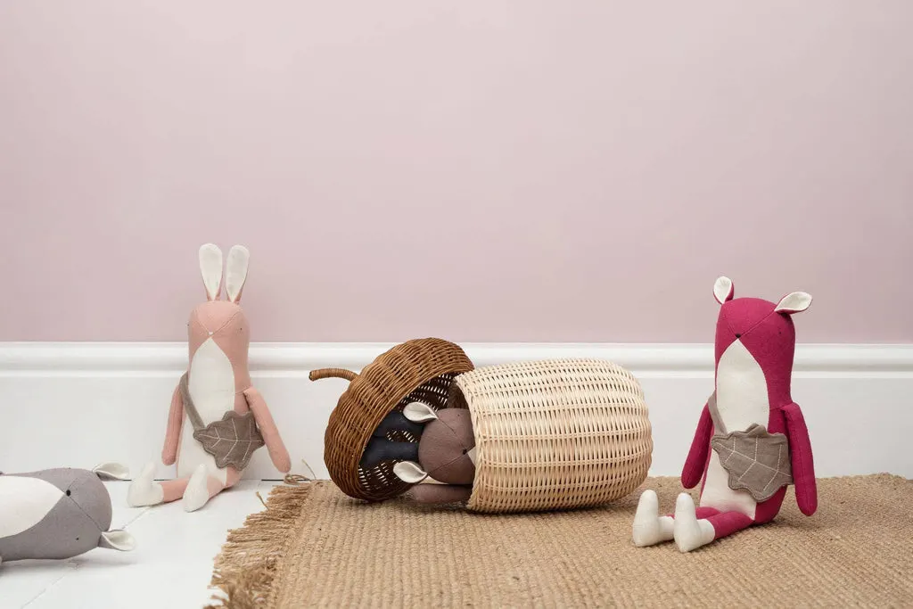 Handmade stuffed animal toys arranged on a woven mat against a pink and white wall.