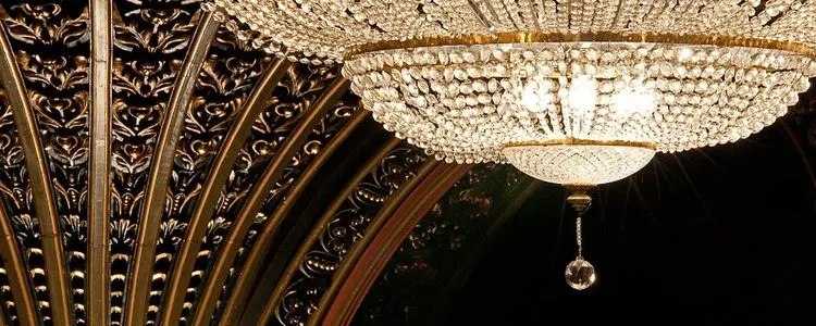 Ornate gilt ceiling with decorative fan-vaulting and crystal chandelier in an elegant theatre interior.
