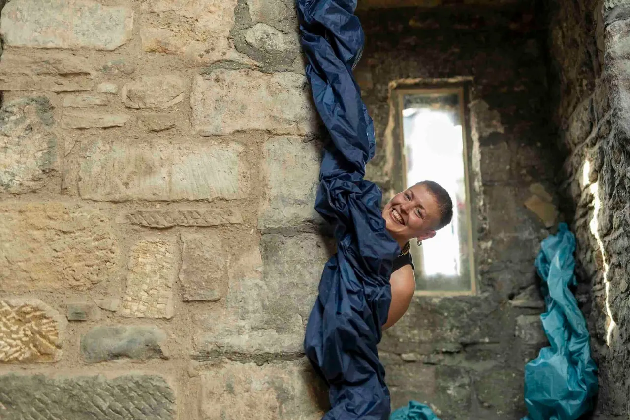Child climbing through narrow stone archway in historic building interior.