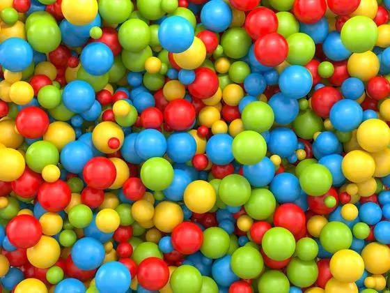 Colourful plastic balls in red, blue, yellow and green filling a ball pit.