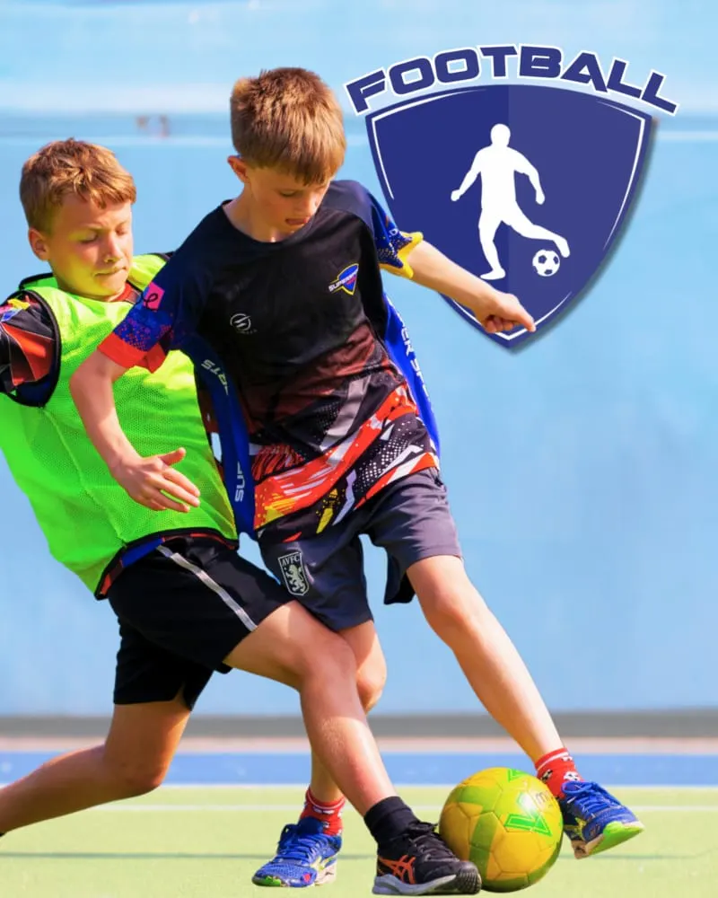 Two young boys playing football indoors, one defending whilst the other controls the ball.