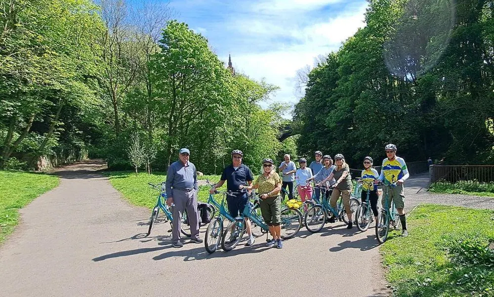 A group of cyclists with their bikes gathered on a tree-lined path during a guided cycling tour.