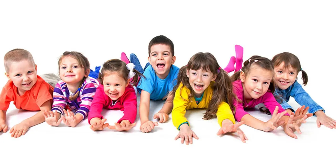 Group of smiling children in colourful clothing crawling and posing together on a white background.