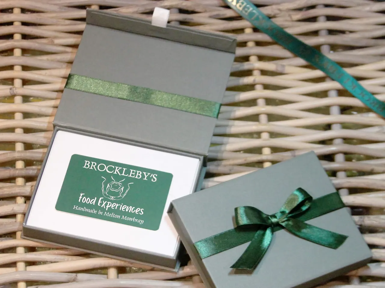 Brocklebys Food Experiences branded gift boxes with green ribbons on woven background.