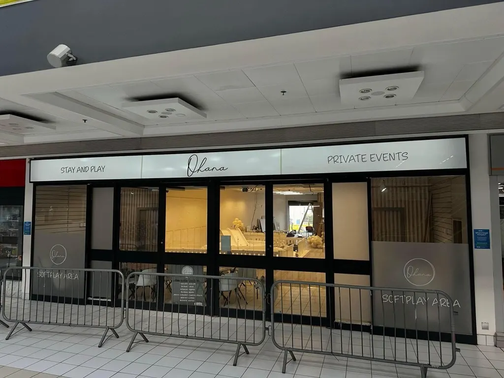 Storefront of a children's leisure venue with glass frontage showing an indoor play area with soft furnishings and equipment visible inside.